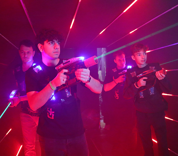 Gruppe Jugendlicher spielt Lasertag und schießt auf Ziel